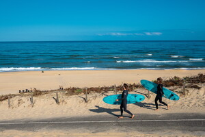 Surfeurs qui descendent la dune pour rejoindre le spot de surf sur la plage du camping 5 étoiles Le Vieux Port